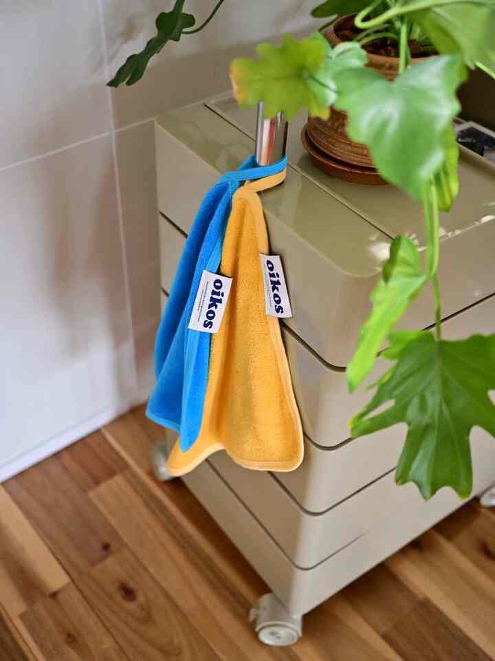 Cozy kitchen space featuring a beige storage cart with yellow and blue kitchen towels hanging and green plants