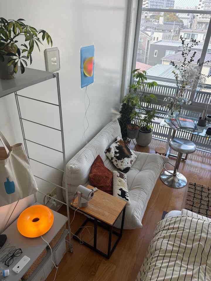 ナチュラルなブラウンウッドの小さな一人暮らしリビング、白いソファと観葉植物が配置された温かみのある空間