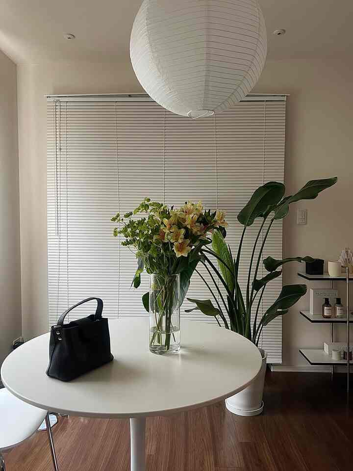 白を基調としたダイニング、丸テーブルの上に花瓶と黒いバッグが置かれたシンプルな印象的な空間