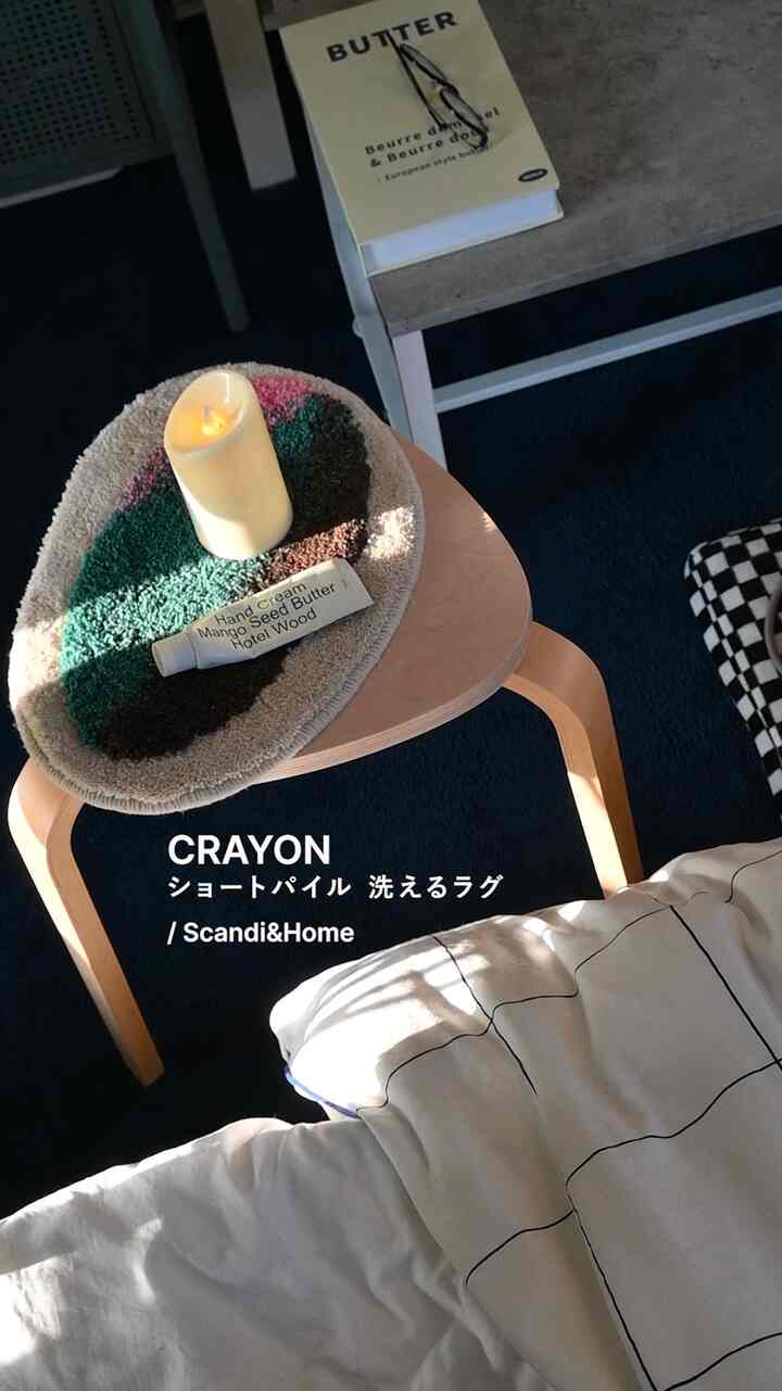 Cozy bedroom with a navy rug and natural wooden stool illuminated by soft sunlight