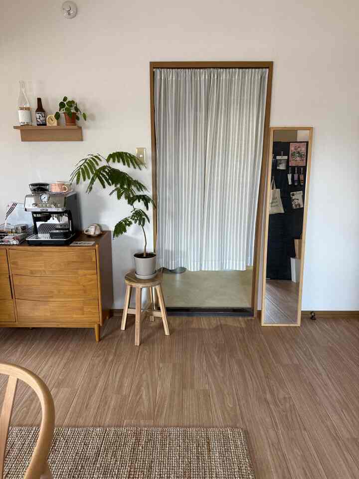 ナチュラルな木目調のリビング、ストライプのカーテンとダイニングチェアが配置された落ち着いた雰囲気の空間