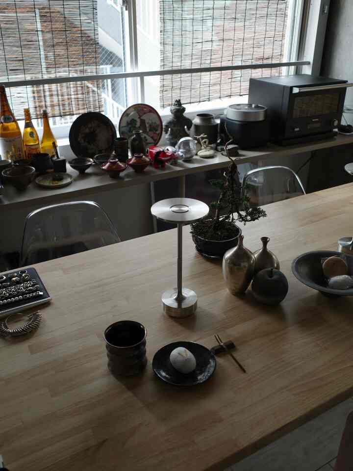 ナチュラルな木目調の1LDKダイニングルーム、透明な椅子と日本伝統の陶器、バルミューダのキッチン家電が調和する印象的な空間