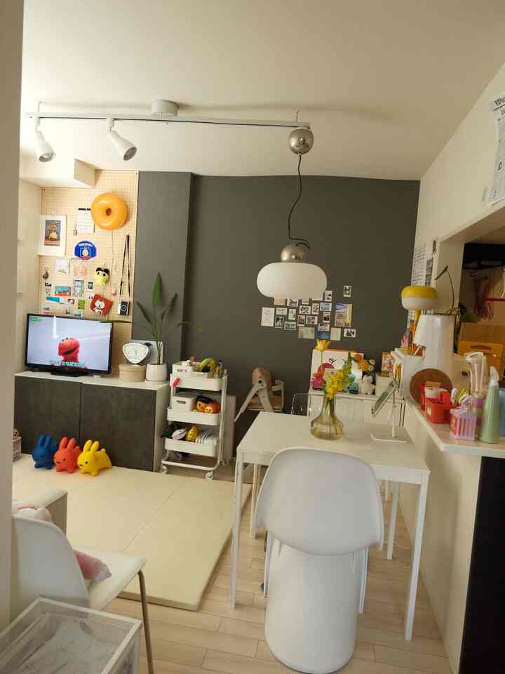 白とグレーのトーンの2LDKリビング、ダイニングテーブルとおもちゃ収納が配置されたシンプルで子供に優しい雰囲気のインテリア