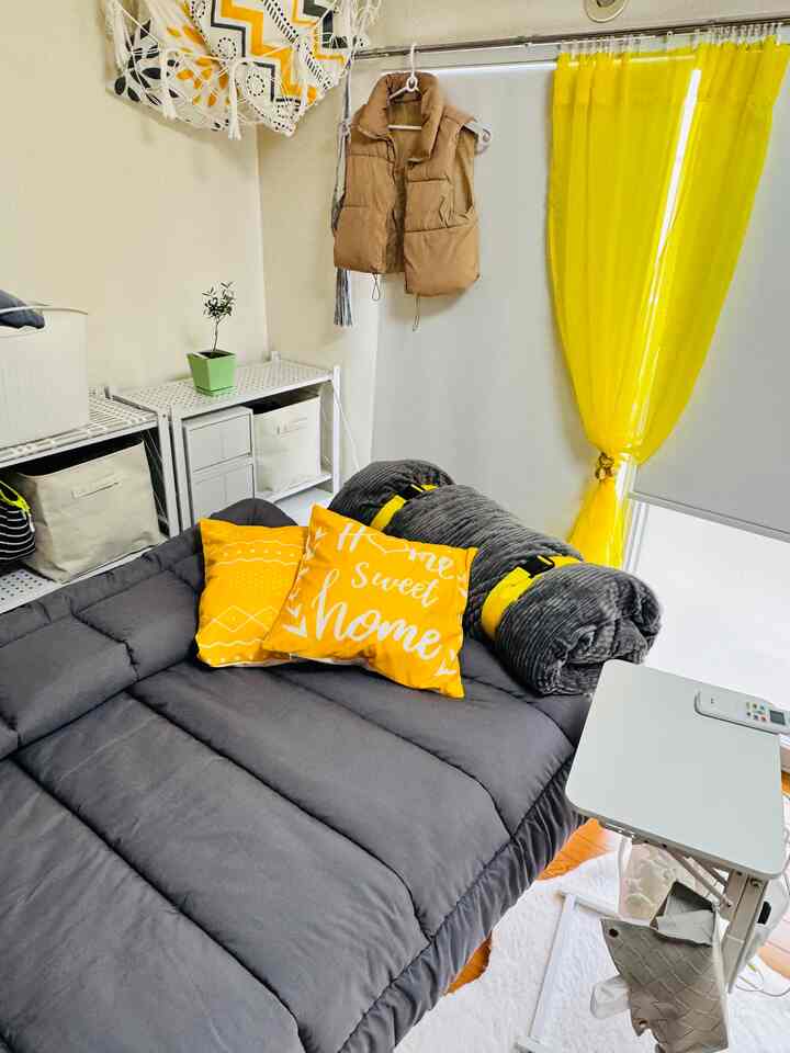 Yellow and gray toned studio bedroom featuring a bed and bright curtains with a cozy atmosphere