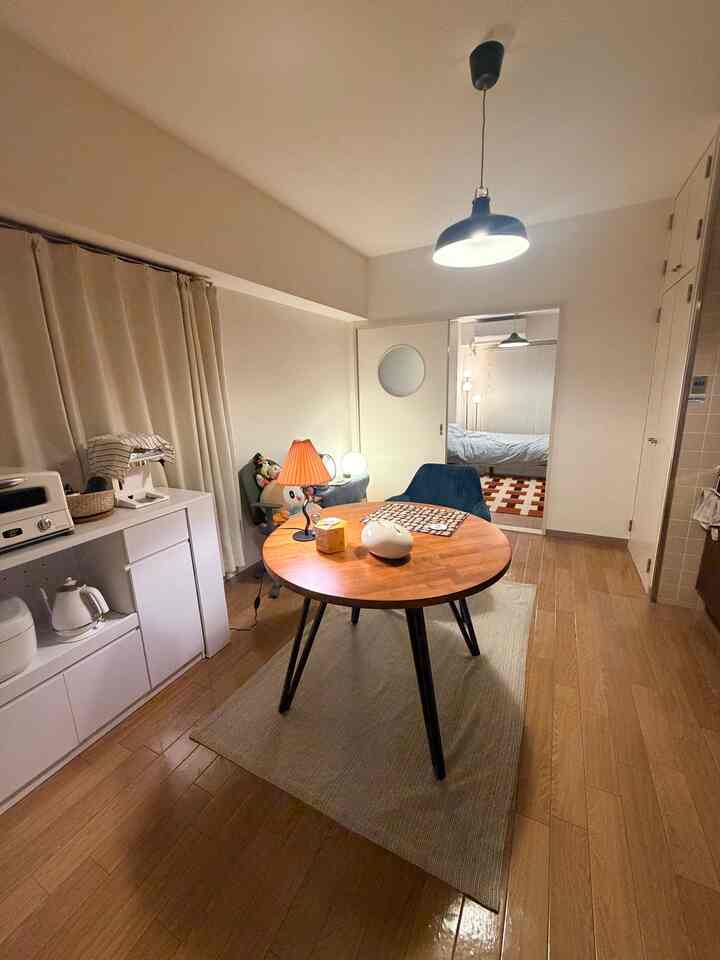Cozy single household dining room in warm brown and white tones, featuring a round table and a glowing table lamp