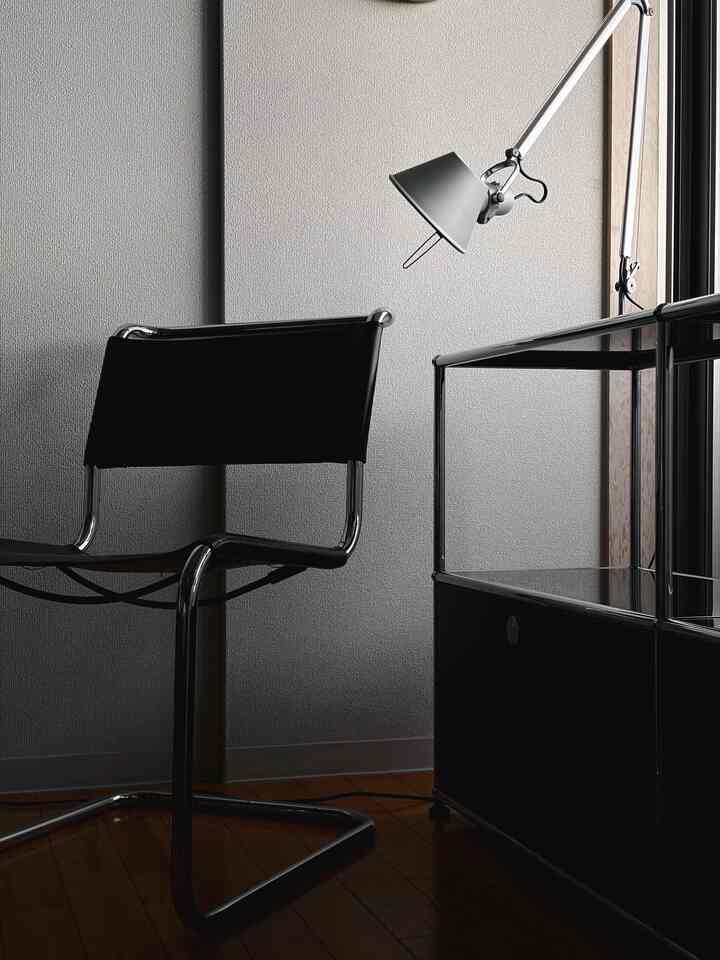 Modern black and silver toned home office space featuring a sleek office chair, task lamp, and cabinet for a quiet work environment