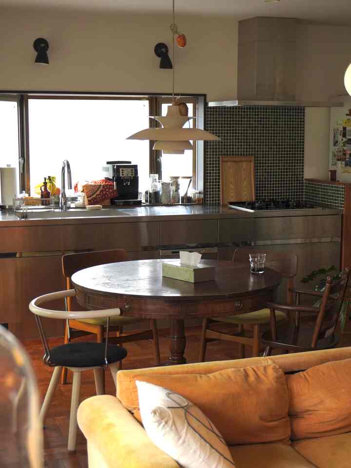 ブラウンの木目調ダイニングルーム、円形ダイニングテーブルと北欧ミッドセンチュリーモダンの椅子が配置された温かみのあるキッチンスペース