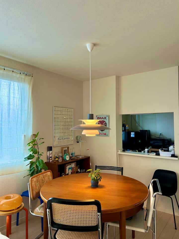 Natural beige-toned dining room featuring a round wooden table with assorted chairs creating a cozy atmosphere