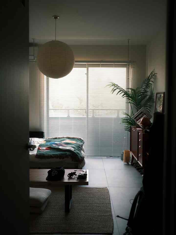 ナチュラルカラーのワンルーム寝室、ウッドベンチとキャビネットが配置され、ブラインドのある落ち着いたインテリア