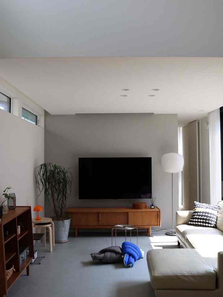 A Nordic mid-century modern living room featuring white walls and wood-tone furniture with a clean, simple layout and indoor plant