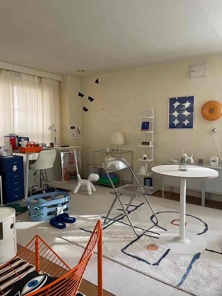 White and blue toned two-person living room featuring mid-century modern furniture, transparent chair, and round table in a cozy setting