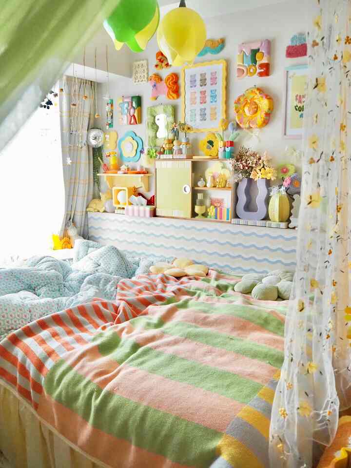 パステルの黄色とピンクが調和した子供部屋の寝室、明るくかわいらしい壁飾りと暖かなブランケットが印象的な空間