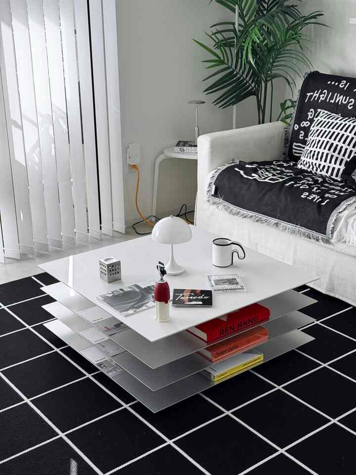 Modern living room in white and black tones featuring a white sofa and layered coffee table with a simple atmosphere
