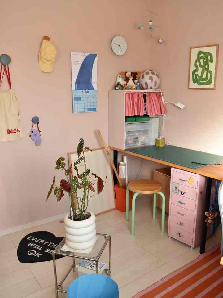 Pink-walled home office featuring mid-century modern furniture, cozy decor, and a plant creating a warm atmosphere