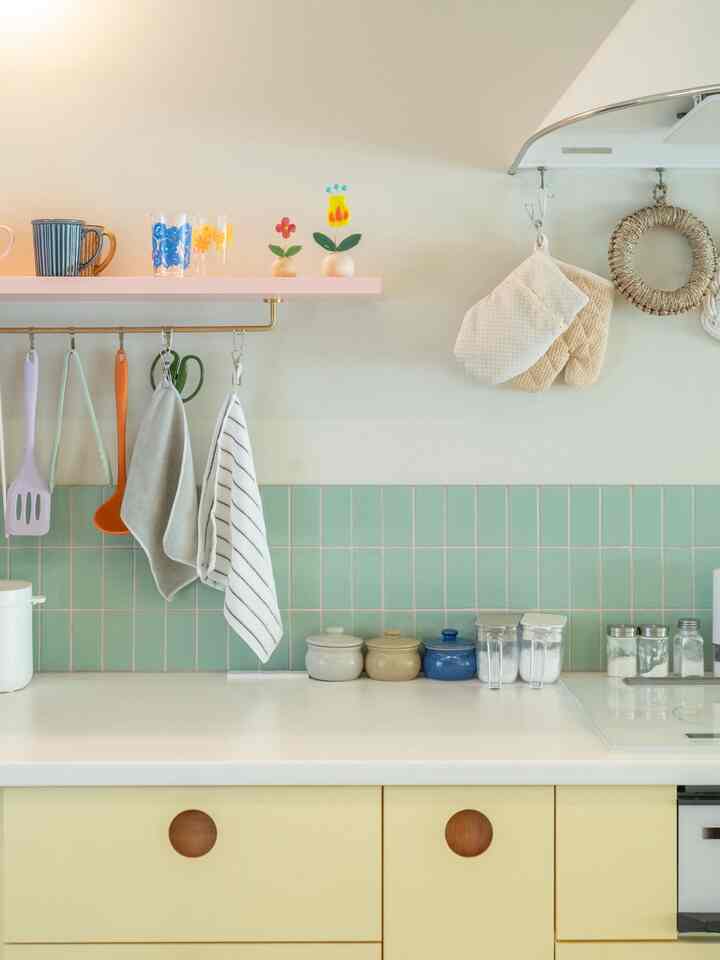 黄色と緑色のトーンのキッチン、調理器具とタオルが整然と配置された雰囲気ある空間