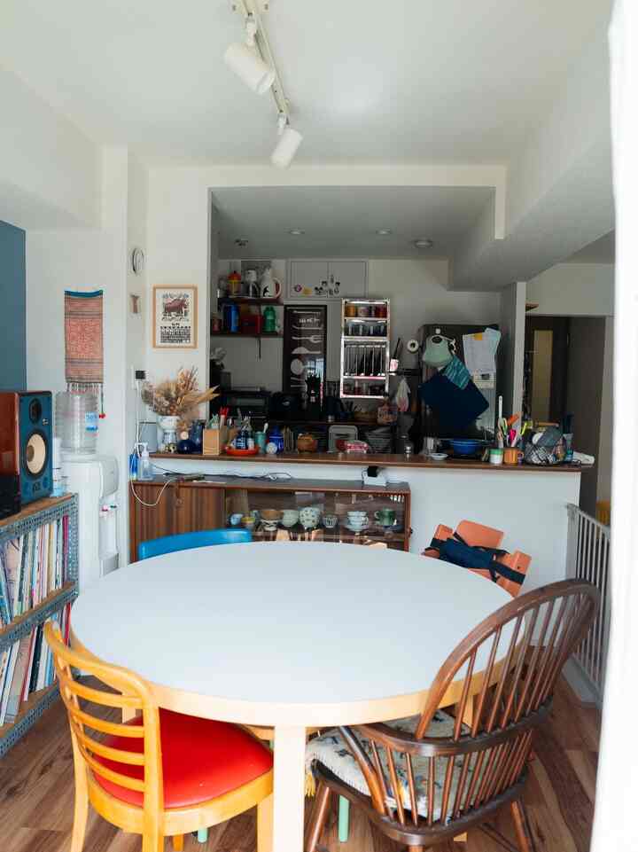 ナチュラルなトーンの北欧風キッチンとダイニングスペース、木製の椅子と白いダイニングテーブルが配置された雰囲気のある空間