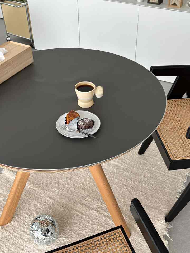 ダークグレーの丸テーブルと木製の脚、ラタンの椅子が置かれたナチュラルな雰囲気のダイニングルーム