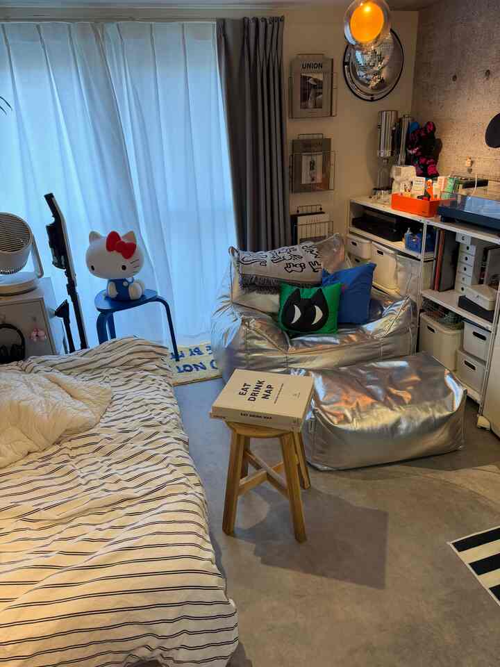 白とシルバーのトーンのコンパクトなワンルーム、メタリックソファと机、ハローキティのインテリア小物が配されたモダンで個性的な雰囲気のあるインテリア