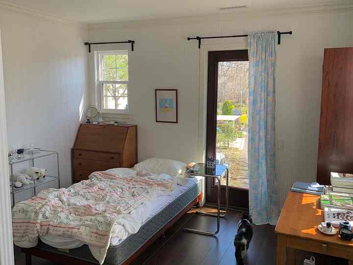 柔らかなナチュラルカラーの寝室、木製ベッドと花柄のブランケットが配置された雰囲気のあるインテリア