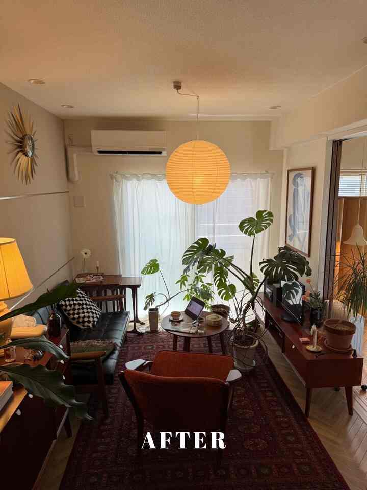 ナチュラルなブラウン調のリビング、ペンダントライトと多様な緑の植物が配置された雰囲気のある空間