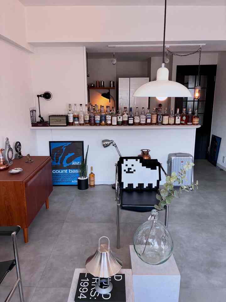 White and brown toned kitchen space featuring mid-century modern furniture and a home bar with various whiskey bottles