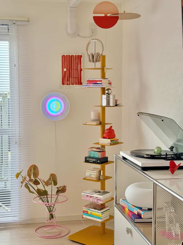 Nordic style study space with white walls and yellow book tower, stylishly featuring a poster and record player