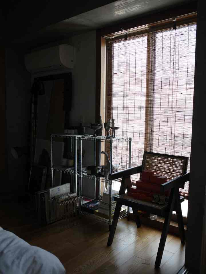 木目調とナチュラルカラーが際立つ一人暮らしの1LDK、竹製ブラインドとラタンの椅子が配置された雰囲気のあるインテリア