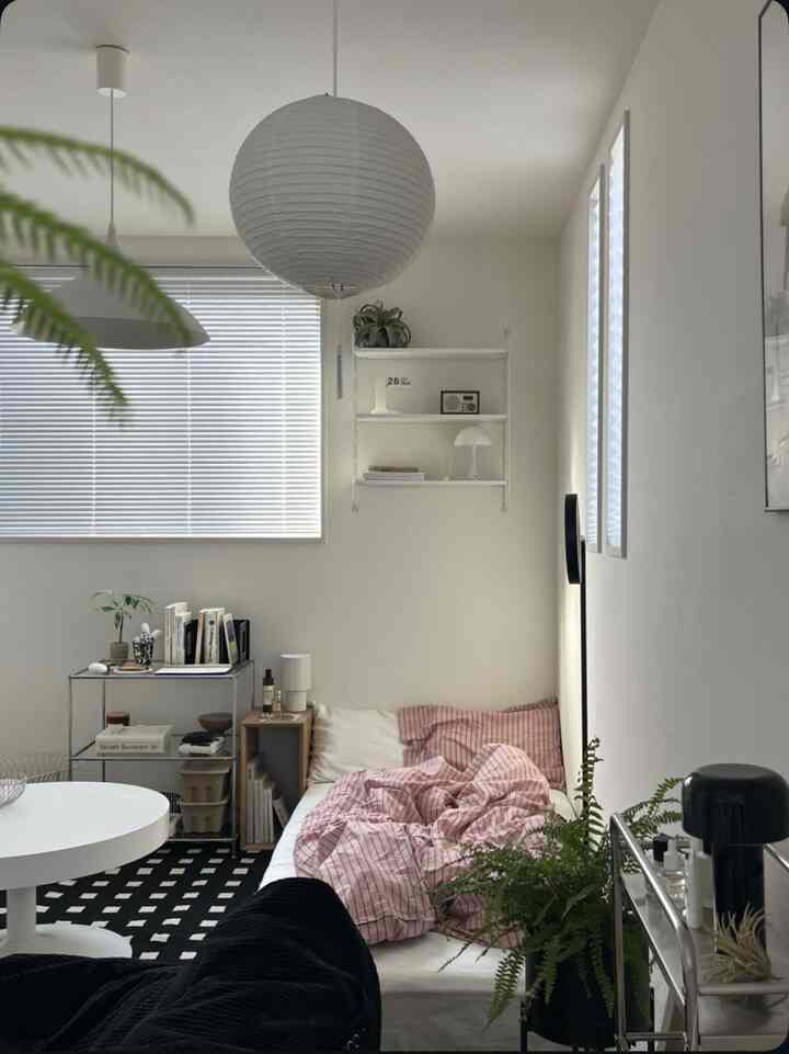White and natural toned small living room featuring low bed, rug, and simple furniture creating a cozy atmosphere