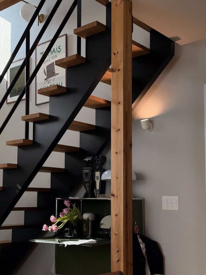 Modern under-stairs desk space with white walls and wood-toned stairs, featuring integrated storage