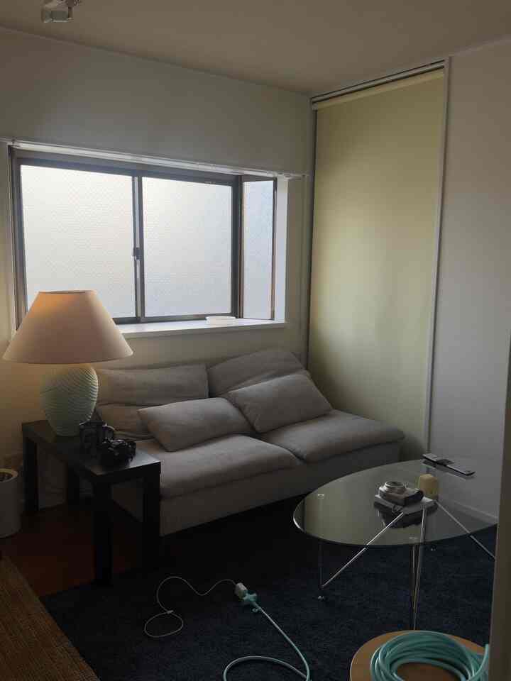 Natural tone living room with beige sofa and transparent glass table, creating a warm and simple atmosphere in a compact space