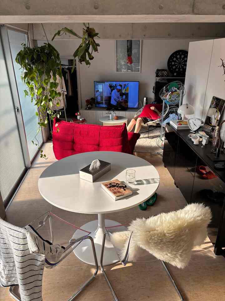 Bright white and red toned living room featuring a red sofa and transparent dining chairs in a simple modern interior