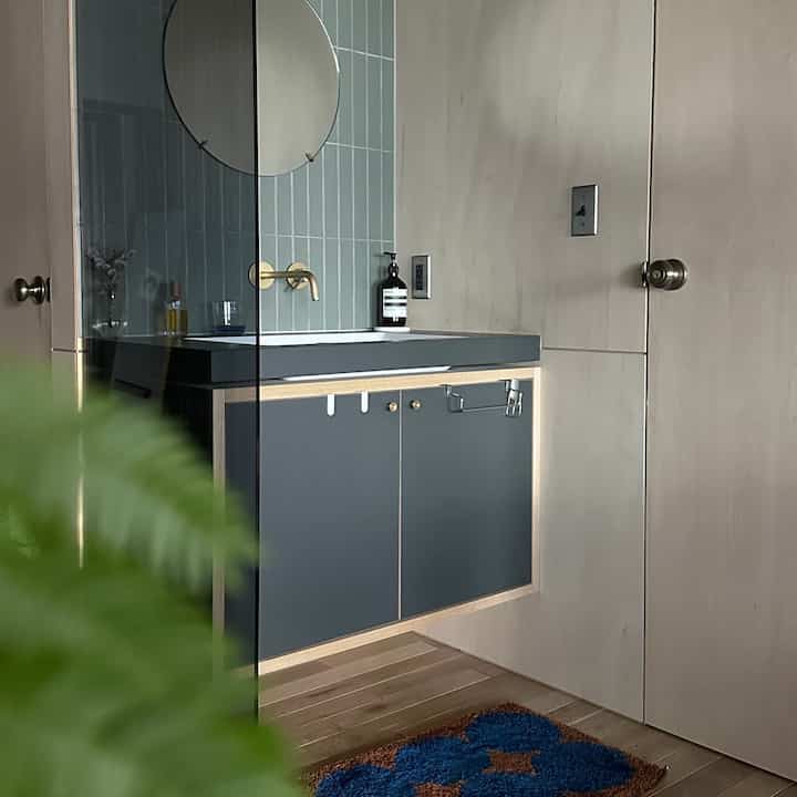Natural toned studio apartment sink area with a glass wall adding transparency in a modern interior