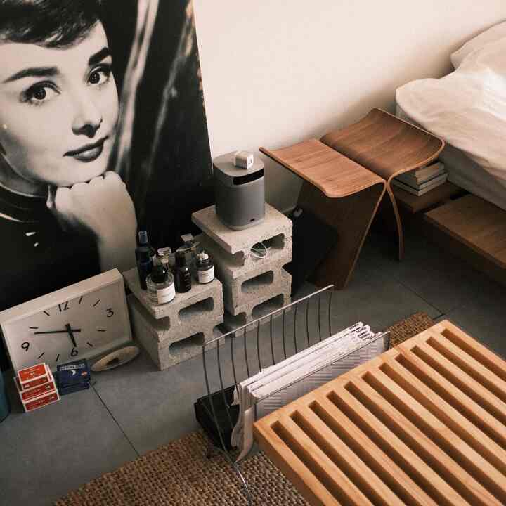 Natural color bedroom featuring wooden stool and concrete block side table with a minimal vibe