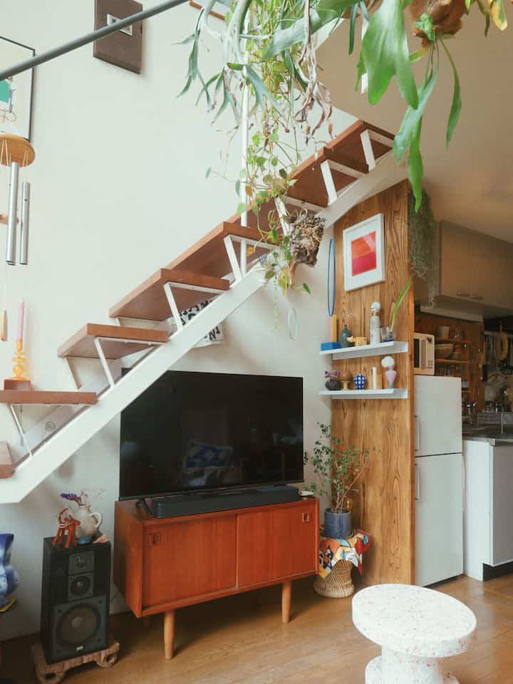白を基調とした壁と木目調の階段、植物が配置された自然な雰囲気のリビング兼キッチンスペース