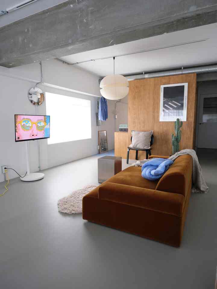 A simple and modern living room featuring white walls, a brown sofa, and natural wood paneling