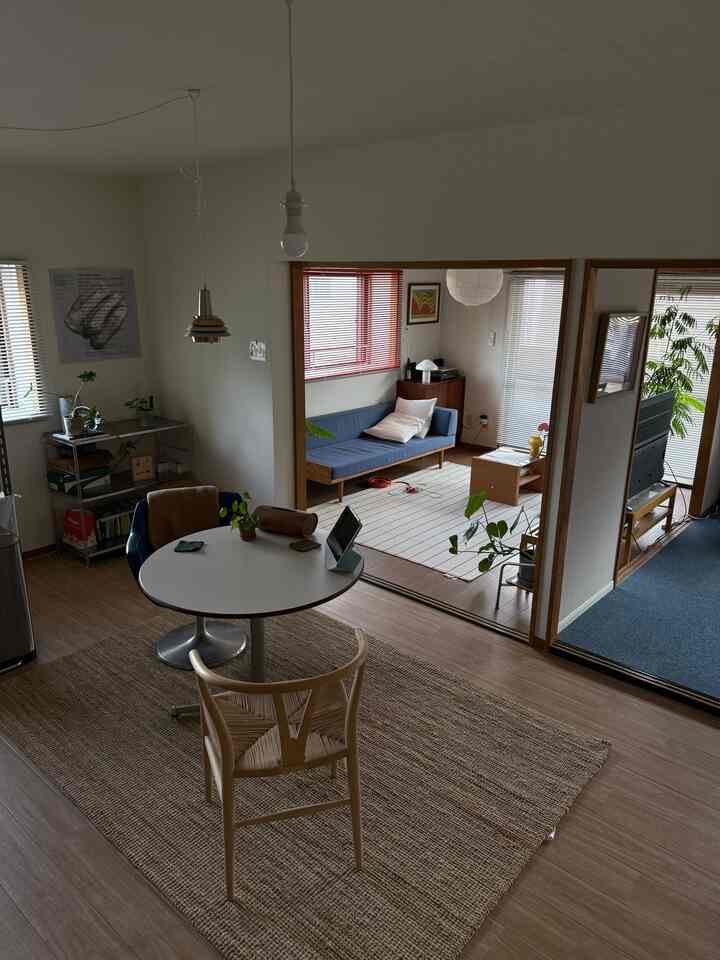Natural tones and white walls characterize a two-person living room featuring a blue sofa and dining table in a warm ambiance