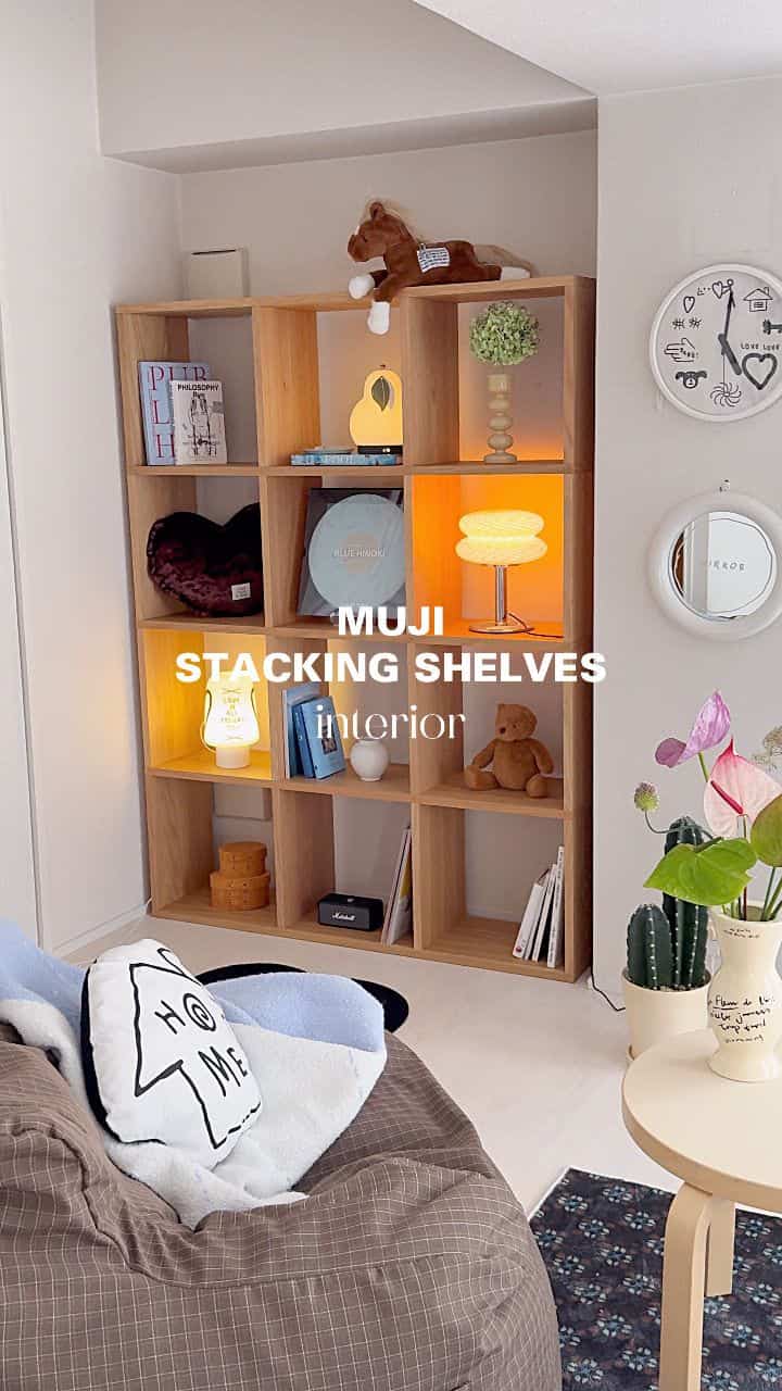 Living room in brown and sky blue tones featuring MUJI stacking shelves, bean bag chair, table lamps, and plants arranged cozy