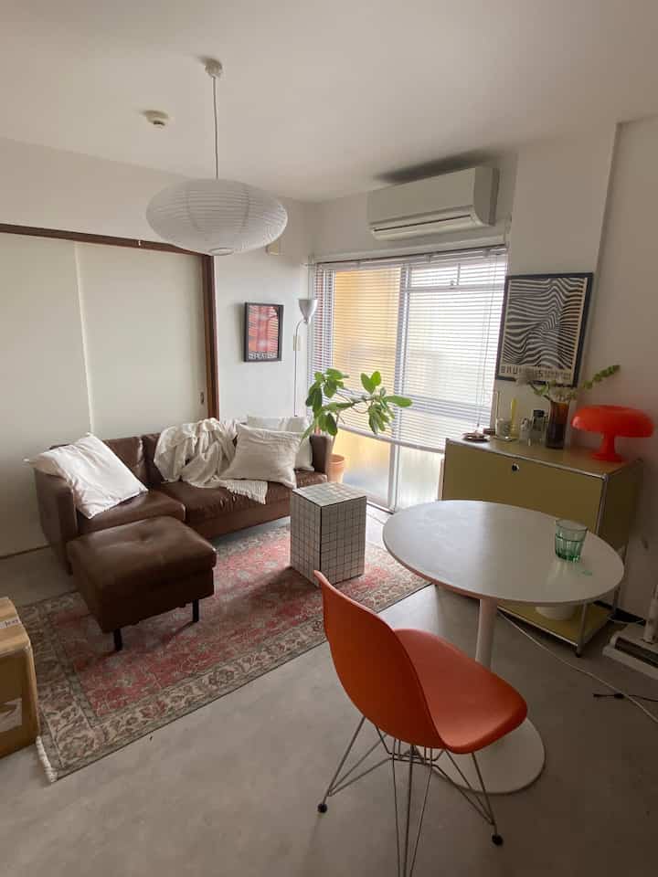 White and brown toned single household living room featuring mid-century modern sofa and orange chair in a cozy atmosphere