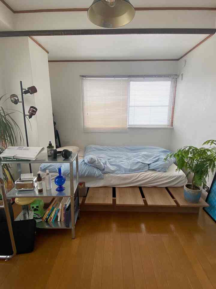 White-walled bedroom with wood-tone floor and storage bed frame for single household, mid-century modern style creating a cozy space