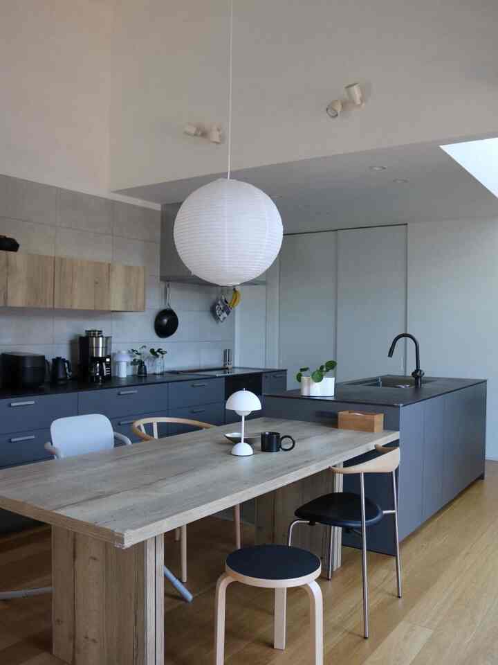 Modern kitchen and dining room in gray and white tones, featuring a large wooden dining table with assorted chairs in a clean setting