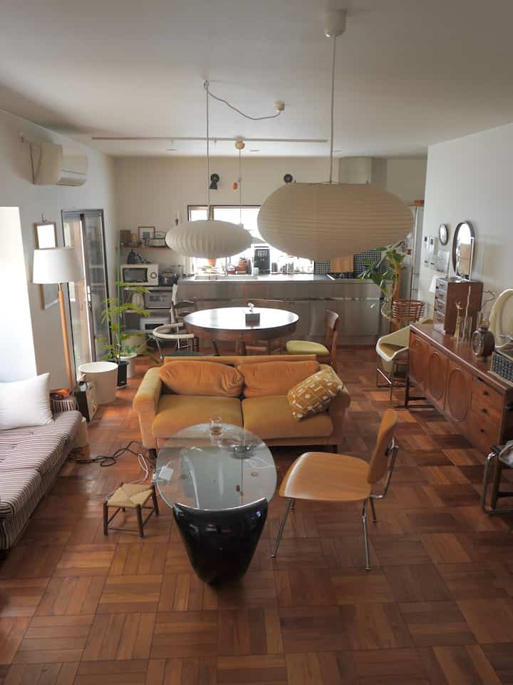 Natural brown-toned living room and kitchen featuring a round dining table and yellow sofa, creating a warm and harmonious interior
