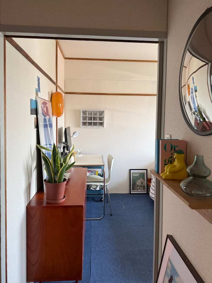 白とナチュラルカラーの狭い部屋、ミッドセンチュリーモダン家具とデスクや植物が配置された韓国風インテリア