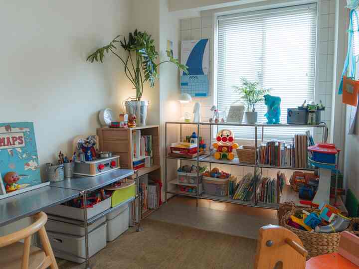 白い壁とナチュラルな木質家具が配された横長の子供部屋、おもちゃや本棚が整頓された雰囲気のあるインテリア