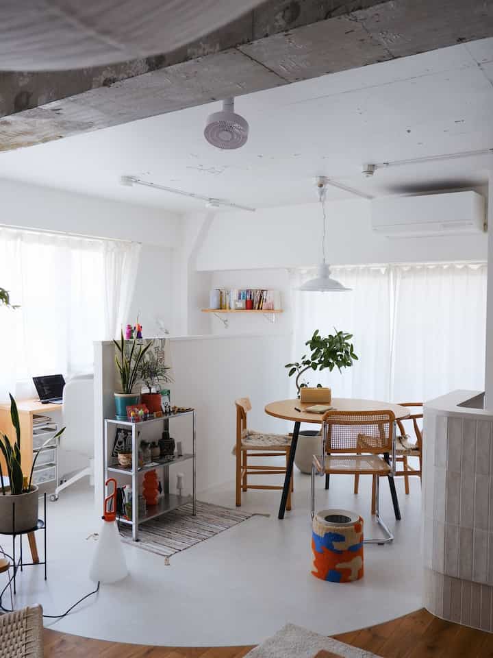 Bright modern dining room in white and natural tones, featuring wooden dining table and chairs with plants