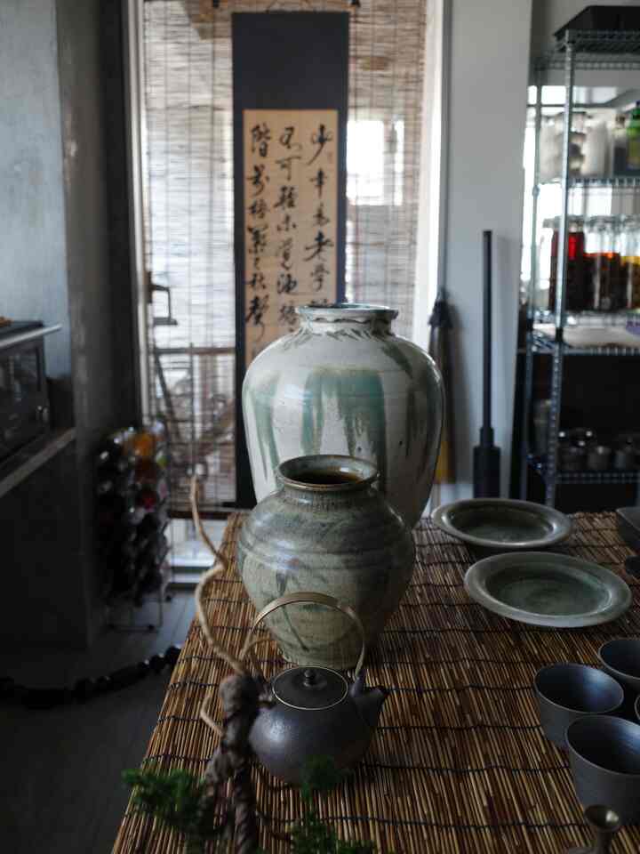 ナチュラルな木目調とアジアン風の雰囲気が漂う一人暮らしの1LDK、竹簾の上に陶器と植木鉢が配置された印象的なインテリア