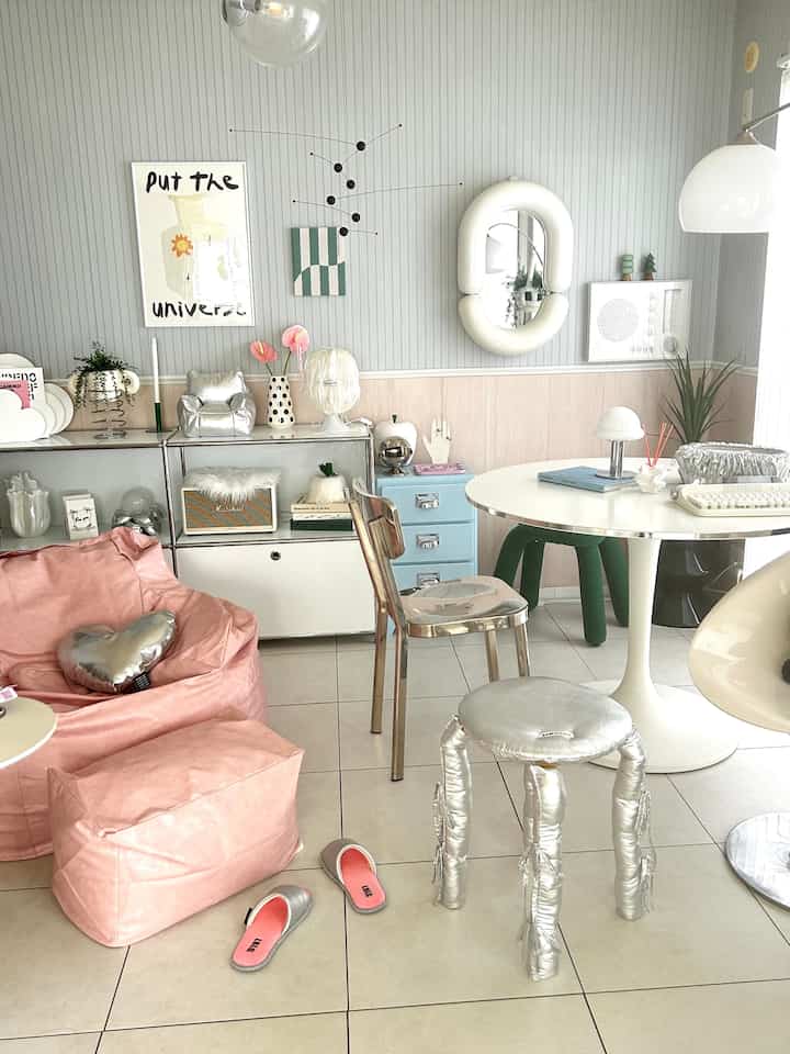 A white and pink toned living room featuring a sofa, table, and vintage accessories in a cozy setting