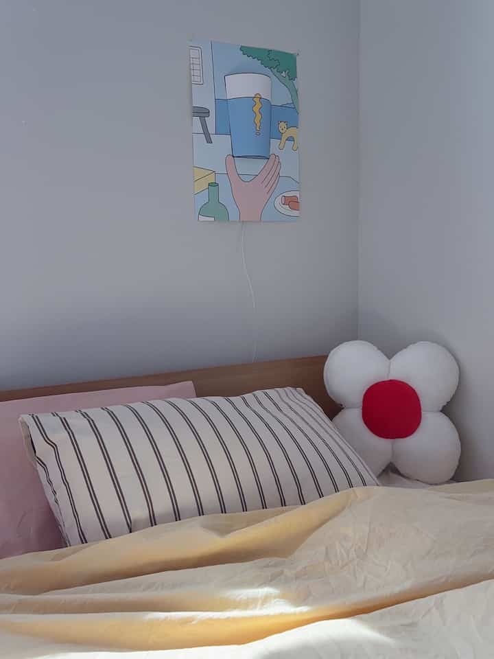 Natural white and beige toned kids' room featuring pink pillows and a cute flower cushion in a cozy bedroom setting