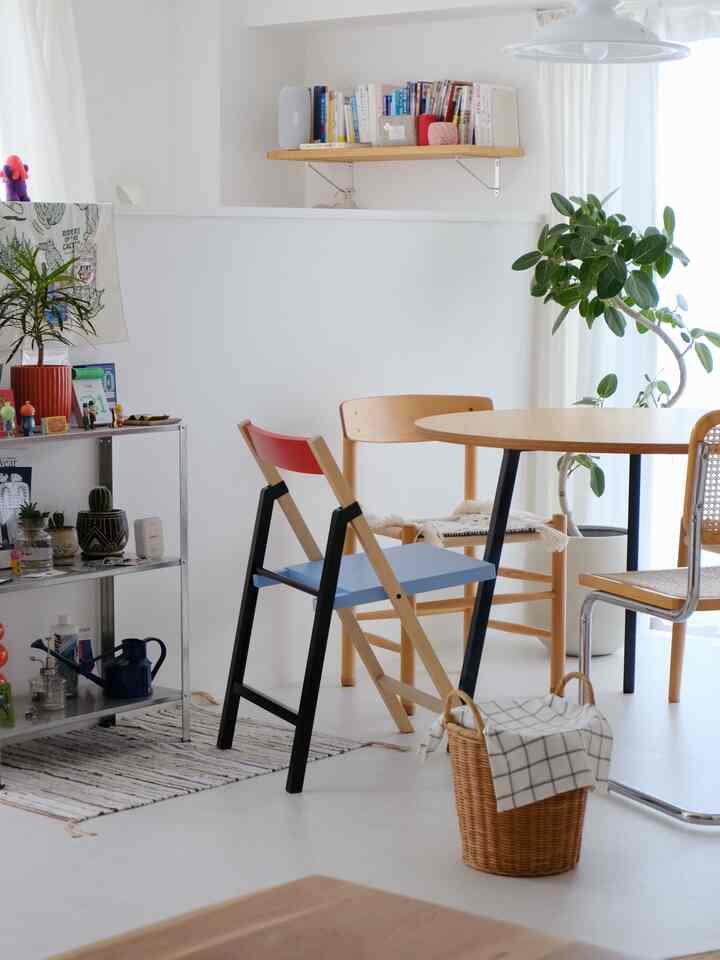 Bright white dining room featuring wooden furniture, a round dining table with varied chairs and plants, creating a cozy atmosphere