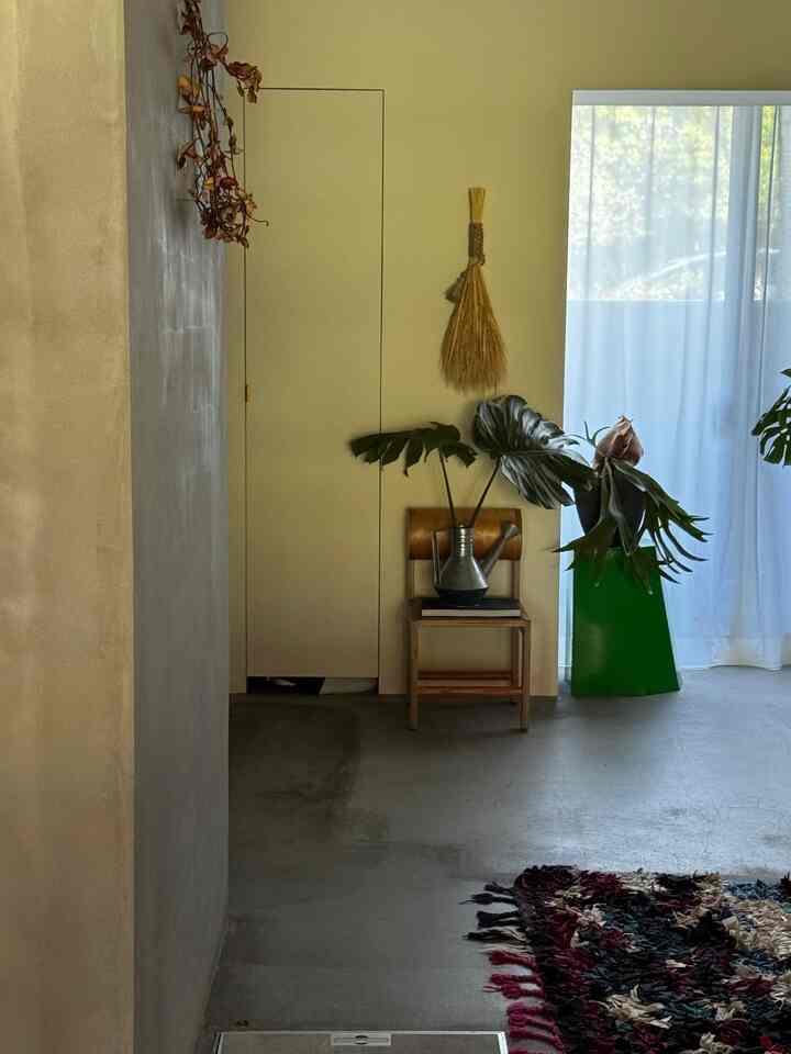 ナチュラルカラーの壁と床、植物や装飾が配置された狭くて落ち着いたコーナースペース