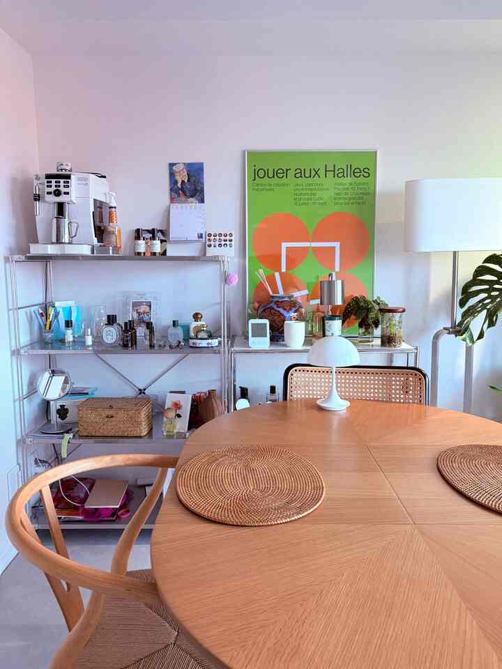 Dining room featuring warm orange poster, silver steel shelves, and natural wood dining table and chairs with cozy atmosphere